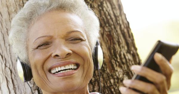 Older woman listening to an audiobook using a phone and headphones