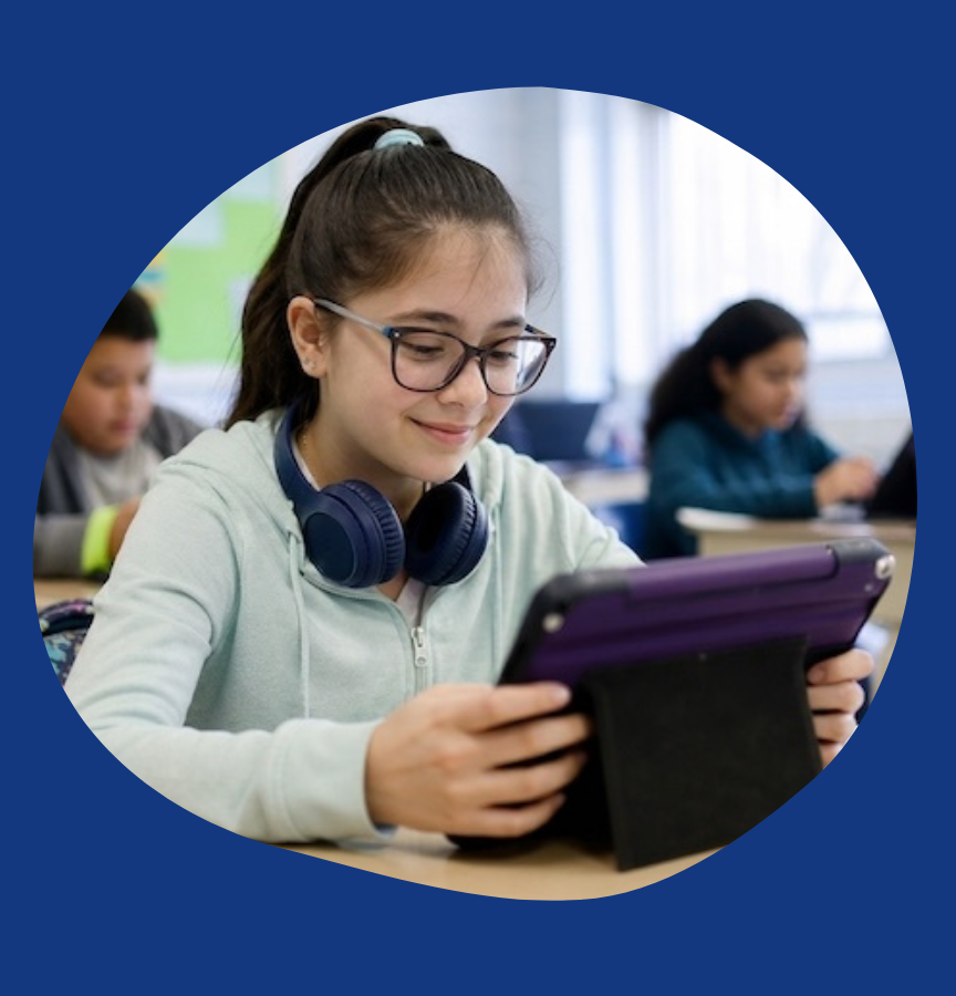 a middle grade school aged girl in a classroom with headphones and reading on a tablet.